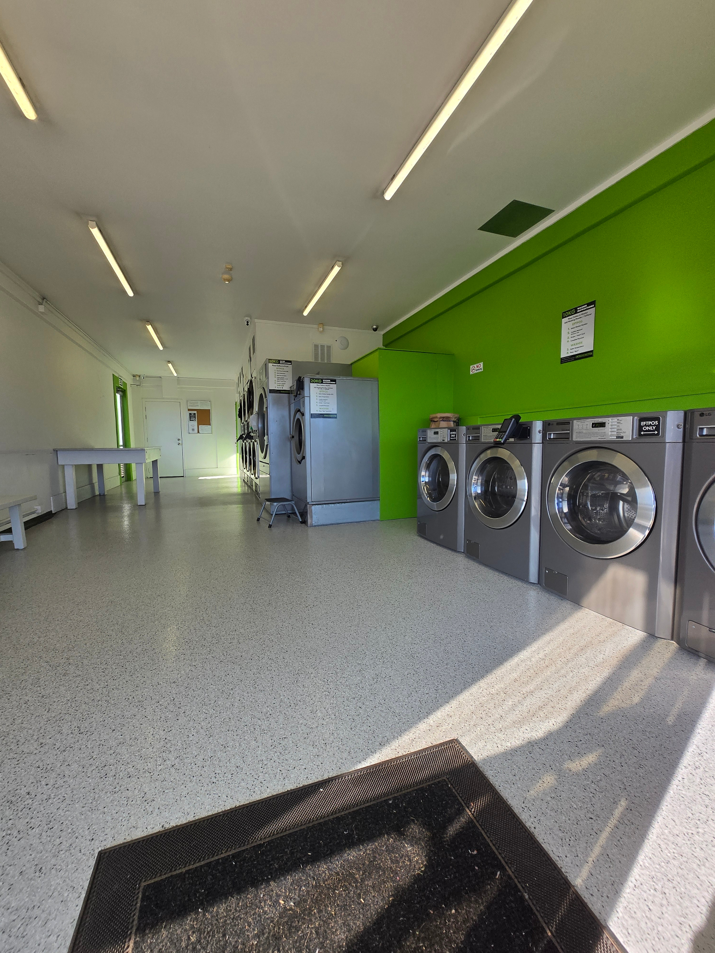 Fifth Ave Laundromat — modern front-load washers along the green feature wall